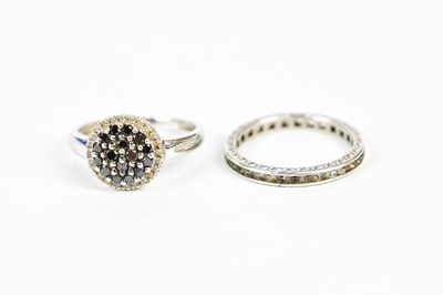 Lot 191 - A white metal dress ring, set with dark stones,...