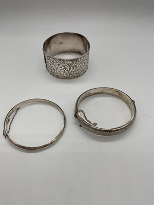 Lot 516 - A broad silver bangle with leaf engraved...