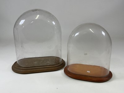 Lot 196 - Two glass domes with oak bases, larger height...