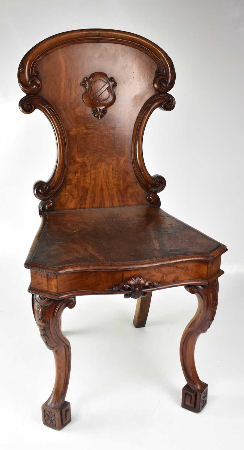 Lot 30 - An oak shield back hall chair raised on carved...