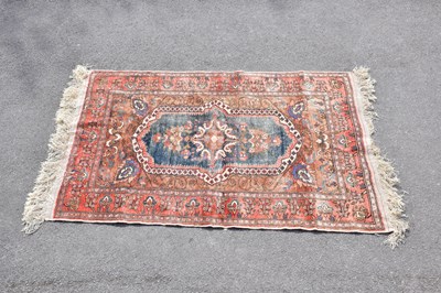 Lot 430 - An orange ground silk carpet with central...