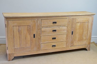 Lot 254 - A modern limed oak sideboard with four drawers...