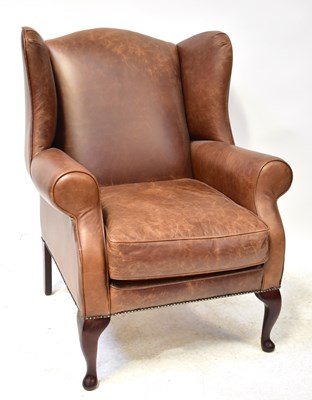 Lot 13 - A modern brown leather wing armchair with...