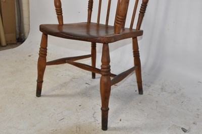 Lot 1486 - An elm seated spindle back elbow chair on...