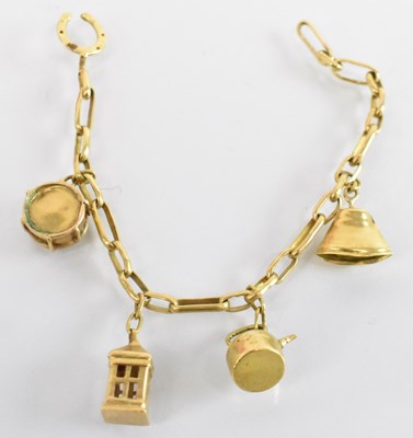 Lot 1266 - A yellow metal charm bracelet including bell,...