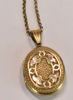 Lot 592 - A yellow metal oval engraved locket suspended...