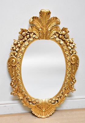 Lot 1039 - A large modern oval ornate gilt wall mirror,...