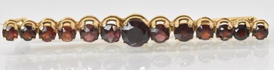 Lot 751 - An 18ct yellow gold garnet set bar brooch, the...