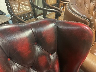 Lot 10 - A modern oxblood red leather button wing back armchair