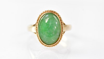 Lot 890 - A 14k ring with bezel set oval jade cabochon...