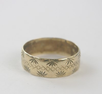 Lot 157 - A broad 9ct yellow gold engraved wedding band,...