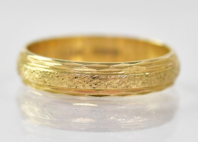 Lot 892 - An 18ct gold ring with textured central band,...