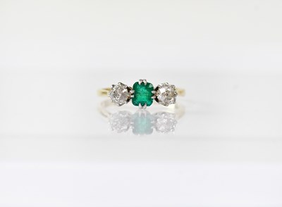 Lot 915 - An 18ct gold ring set with a central emerald...