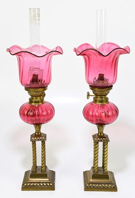 Lot 204 - A pair of brass and cranberry glass peg lamps...