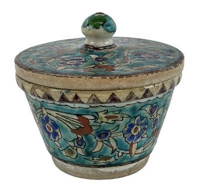 Lot 1087 - An Islamic tin glazed floral decorated lidded...