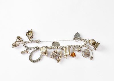 Lot 765 - A silver charm bracelet with thirteen charms,...