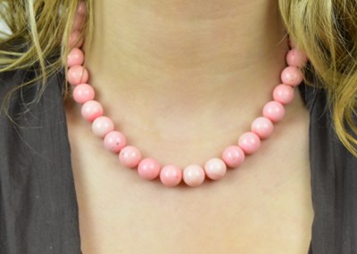 Lot 622 - A coral coloured bead necklace, with white...