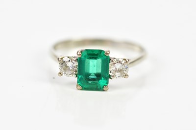 Lot 57 - An 18ct white gold emerald and diamond three...