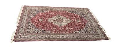 Lot 1255 - A red ground eastern style rug with central...