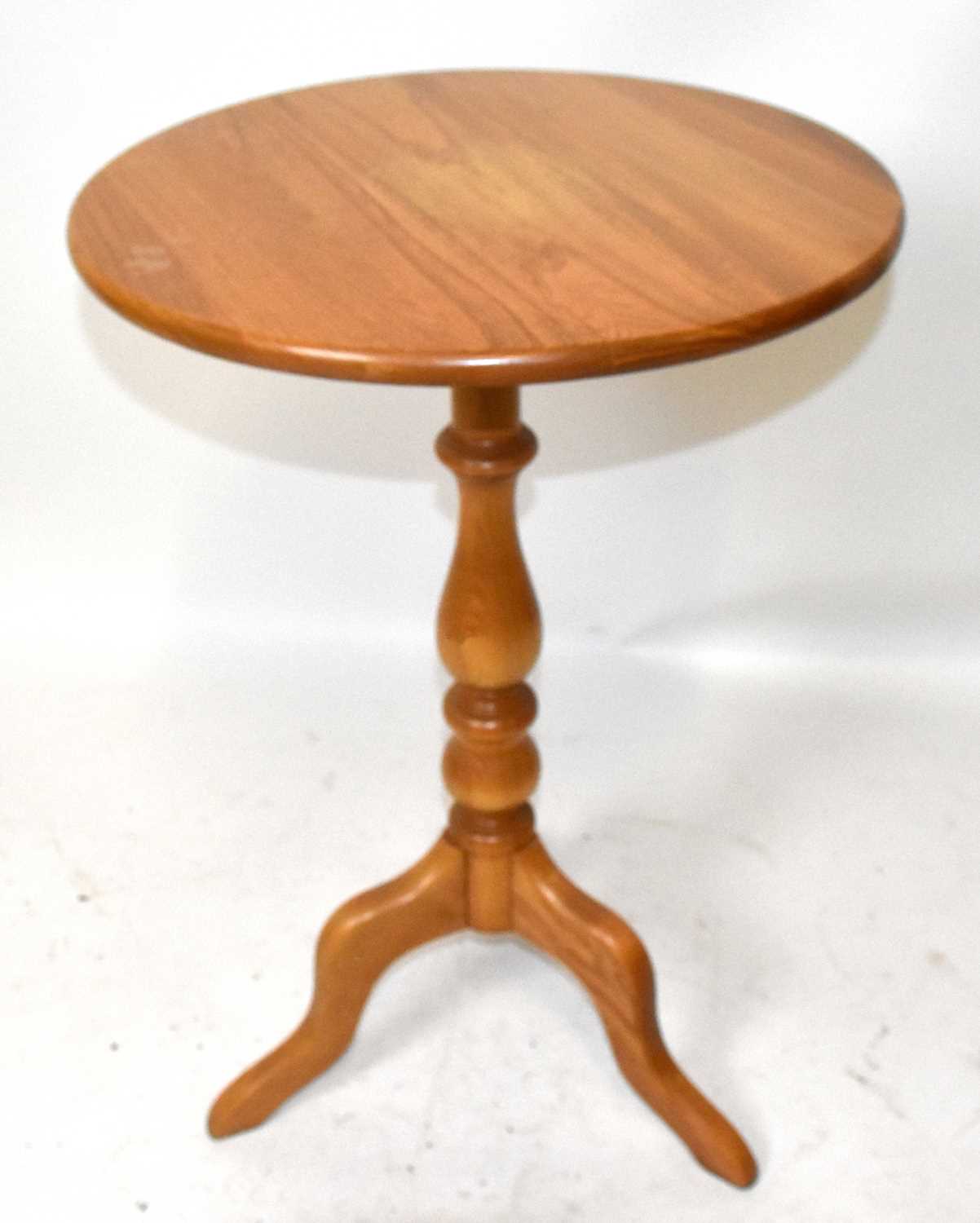 Lot 575 - ERCOL; a light elm tripod table, height 75cm.