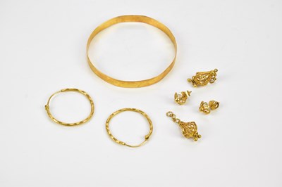 Lot 7 - A yellow metal bangle with chased decoration,...