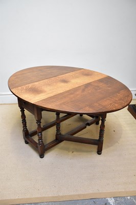 Lot 104 - An oak oval drop-leaf dining table with end...