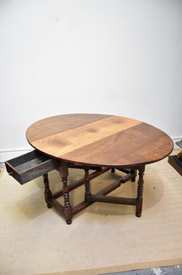 Lot 104 - An oak oval drop-leaf dining table with end...