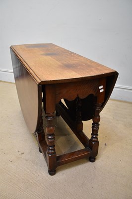 Lot 104 - An oak oval drop-leaf dining table with end...