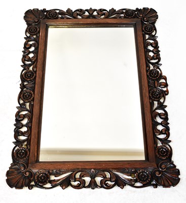 Lot 94 - A carved oak wall mirror with pierced foliate...