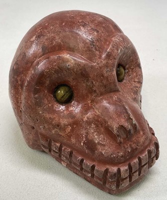 Lot 1036 - A South American carved red stone monkey skull...