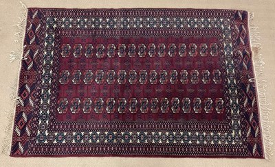 Lot 737 - A machine woven Afghan style rug, claret in...