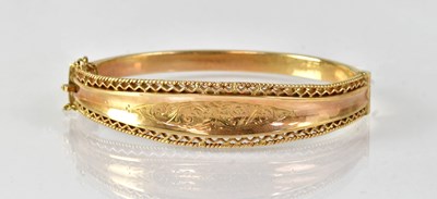 Lot 858 - A 9ct yellow gold hinged bangle with safety...