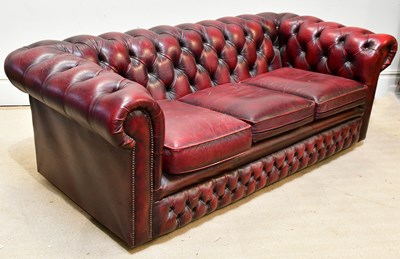 Lot 105 - A button back red leather three seater...